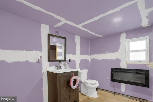 bathroom with hardwood / wood-style flooring, vanity, heating unit, and toilet