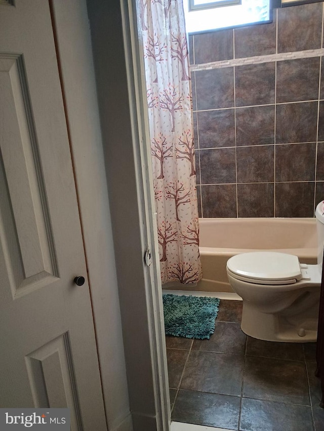 bathroom featuring shower / bathtub combination with curtain, tile patterned floors, and toilet