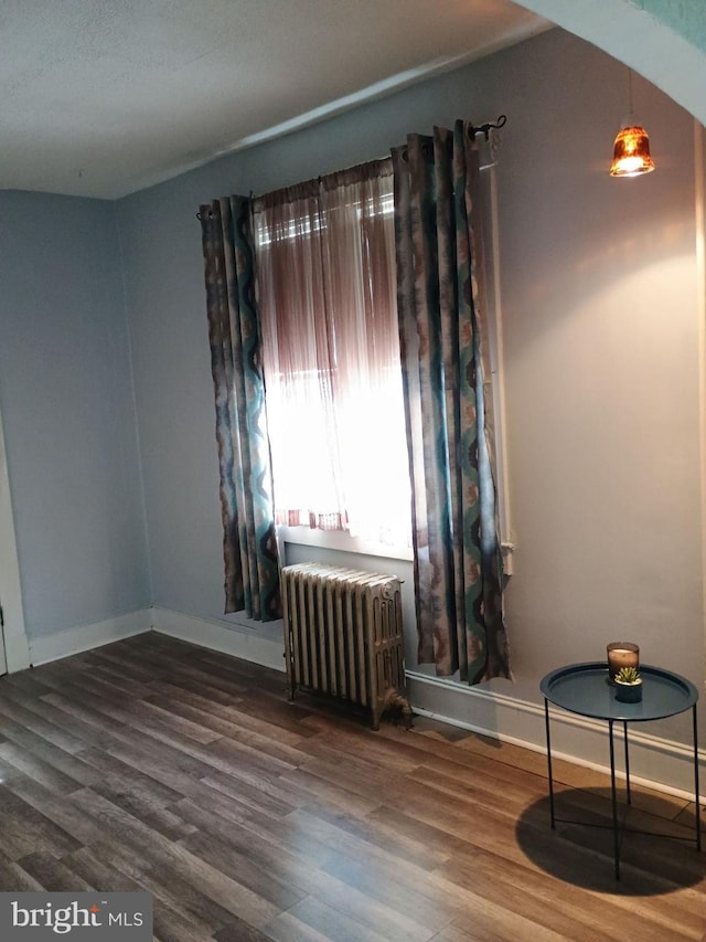 spare room with hardwood / wood-style floors and radiator heating unit