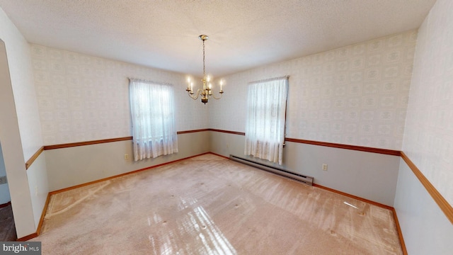 spare room with carpet floors, a baseboard heating unit, a chandelier, and a textured ceiling