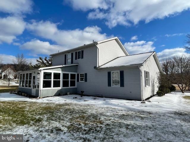 snow covered property with a sunroom