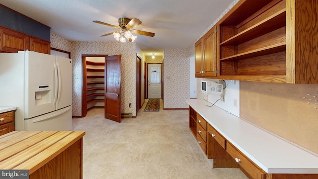 kitchen with built in desk, wooden counters, white fridge with ice dispenser, and ceiling fan