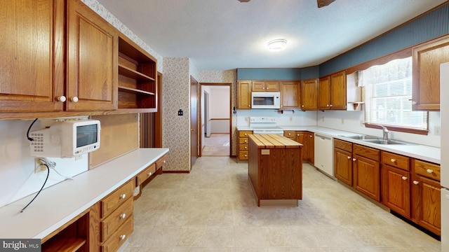 kitchen with sink, wooden counters, a center island, white appliances, and a textured ceiling