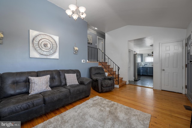 living room featuring lofted ceiling, hardwood / wood-style flooring, and a chandelier