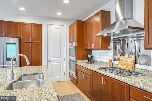 kitchen featuring sink, extractor fan, light stone counters, light hardwood / wood-style flooring, and appliances with stainless steel finishes