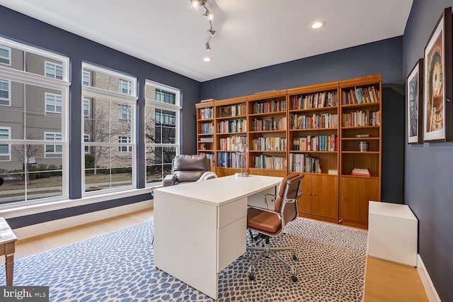 office space with light hardwood / wood-style flooring and rail lighting