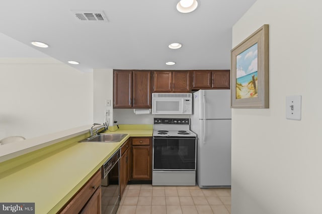 kitchen featuring sink, light tile patterned floors, and white appliances