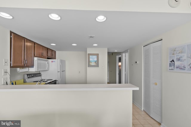 kitchen with light tile patterned floors, white appliances, and kitchen peninsula