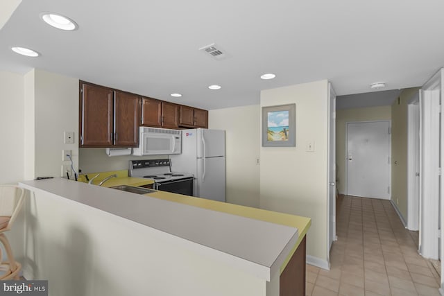 kitchen with sink, white appliances, kitchen peninsula, and light tile patterned floors