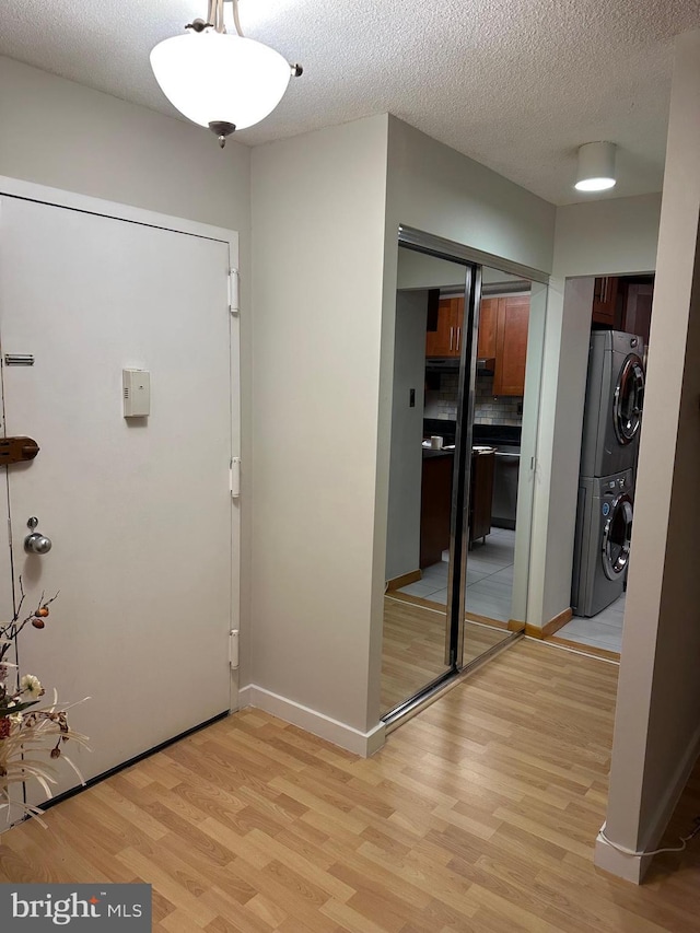 foyer featuring stacked washer / dryer, a textured ceiling, and light wood-type flooring