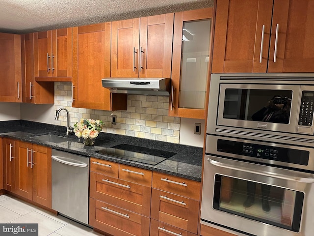 kitchen with stainless steel appliances, sink, dark stone countertops, and decorative backsplash