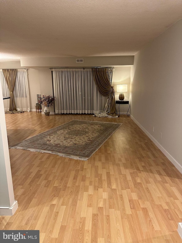 unfurnished room featuring light hardwood / wood-style flooring and a textured ceiling