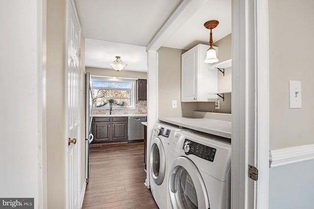 clothes washing area featuring cabinets, washer and clothes dryer, dark hardwood / wood-style flooring, and sink