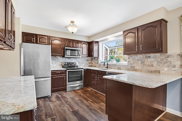 kitchen featuring sink, stainless steel appliances, dark wood-type flooring, kitchen peninsula, and tasteful backsplash