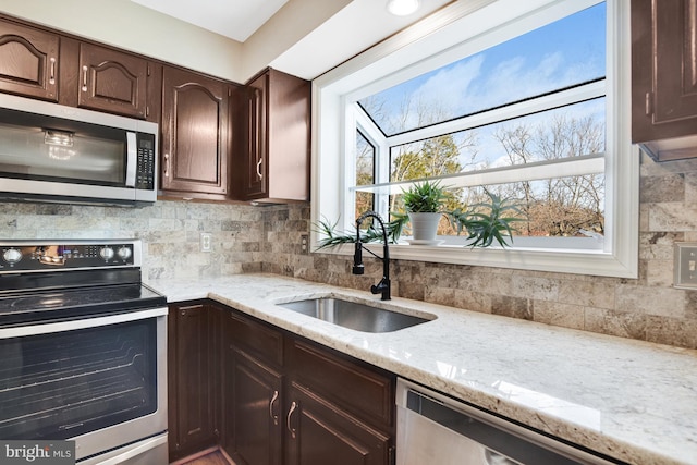 kitchen featuring sink, stainless steel appliances, dark brown cabinets, light stone countertops, and tasteful backsplash