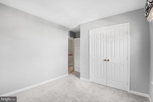 unfurnished bedroom with light carpet and a closet