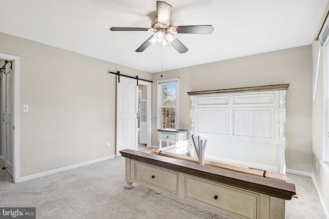 interior space featuring ceiling fan, a barn door, and light colored carpet