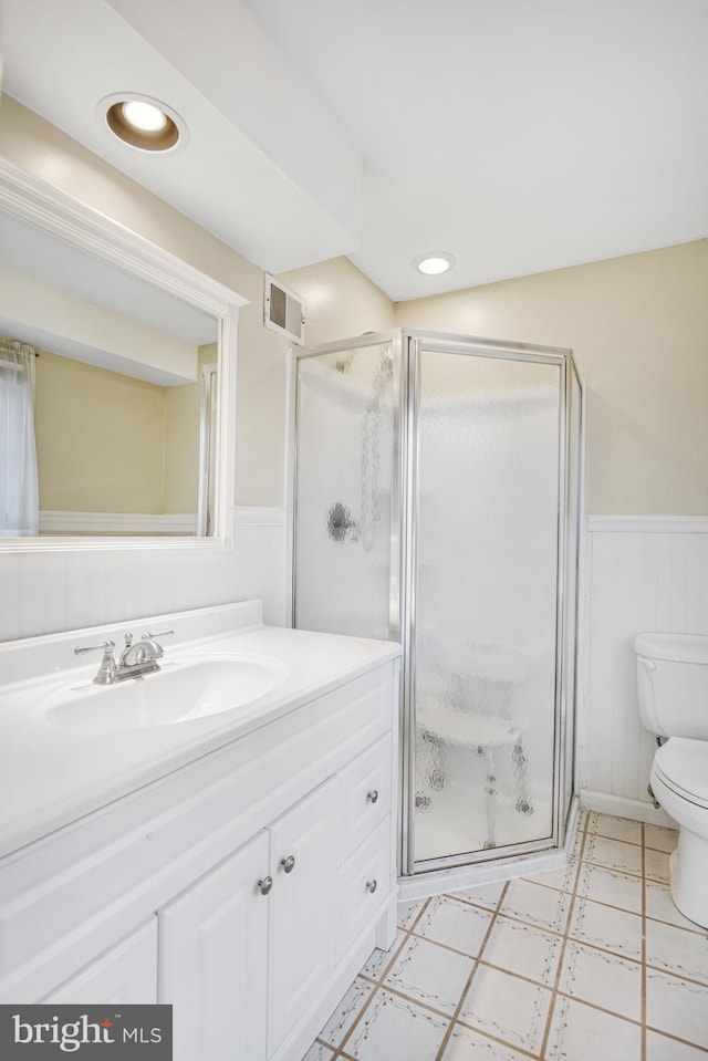 bathroom with toilet, vanity, and a shower with shower door