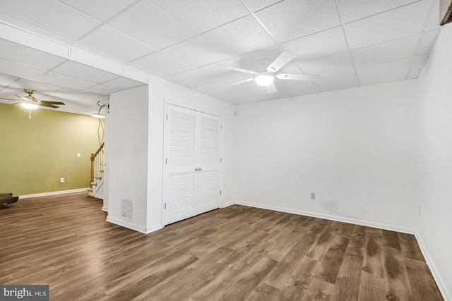 basement featuring ceiling fan, dark wood-type flooring, and a paneled ceiling