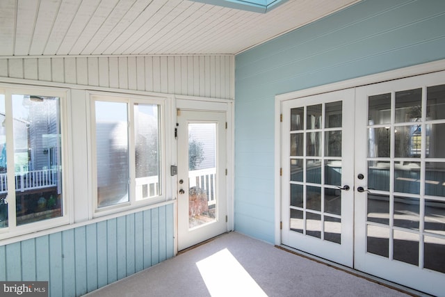 doorway to outside featuring carpet, french doors, wood walls, and lofted ceiling