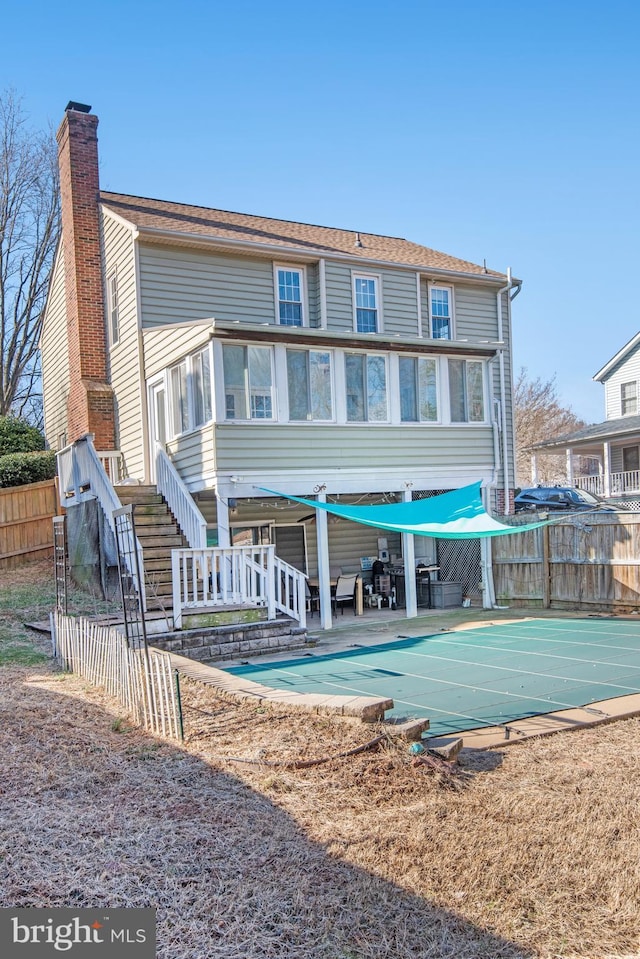 back of property featuring a covered pool, a sunroom, and a patio area