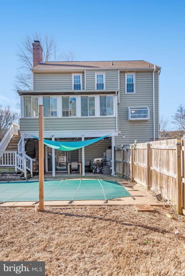 back of house with a covered pool, a patio, and a sunroom