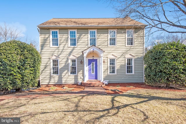 colonial home featuring a front lawn