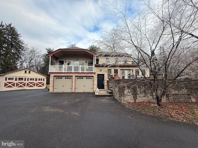 view of front of property featuring a garage, a balcony, and an outdoor structure