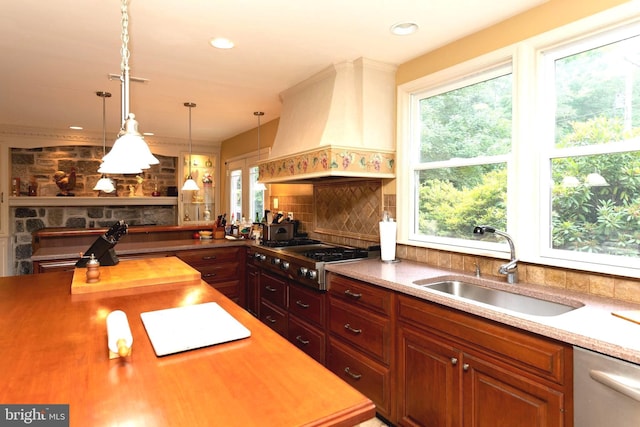 kitchen featuring pendant lighting, sink, stainless steel appliances, decorative backsplash, and custom exhaust hood