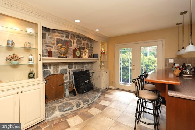 interior space featuring light tile patterned flooring, a wood stove, built in features, and french doors