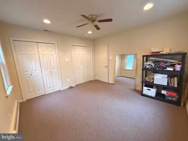 unfurnished bedroom featuring two closets, a baseboard radiator, and carpet