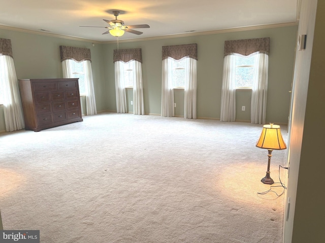 empty room with crown molding, ceiling fan, carpet, and a wealth of natural light