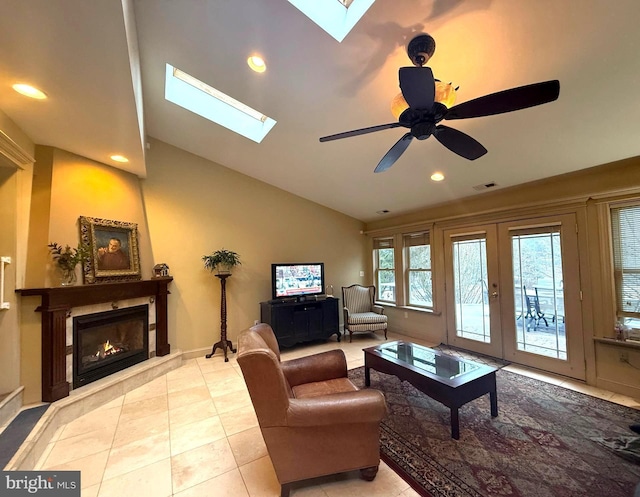 living room featuring lofted ceiling with skylight, light tile patterned floors, ceiling fan, and french doors