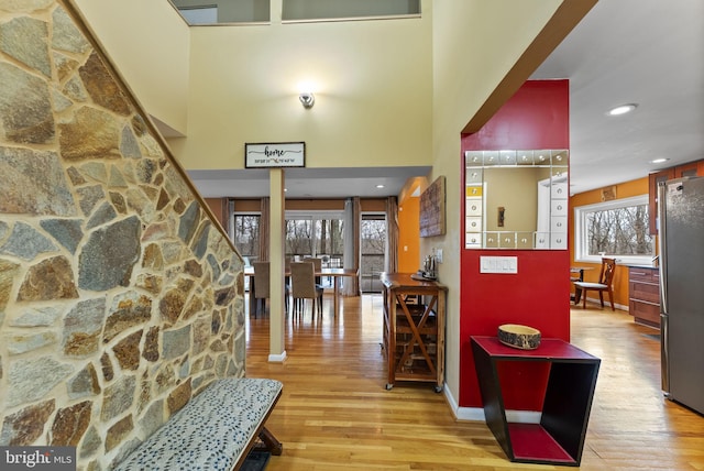 entrance foyer with baseboards, light wood finished floors, a towering ceiling, and recessed lighting