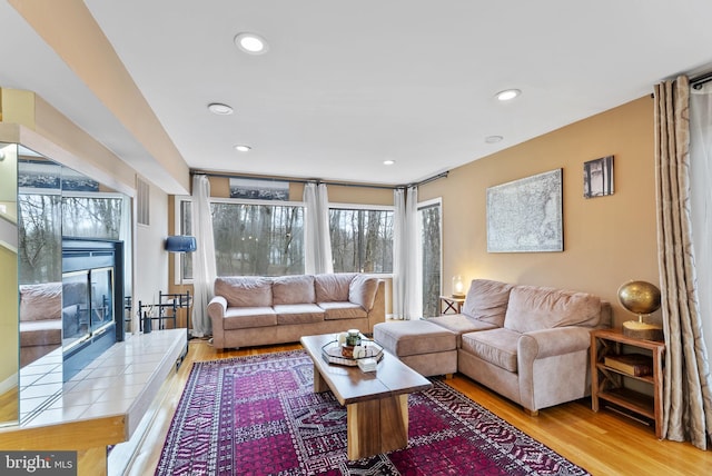 living room featuring a tile fireplace, wood finished floors, and recessed lighting