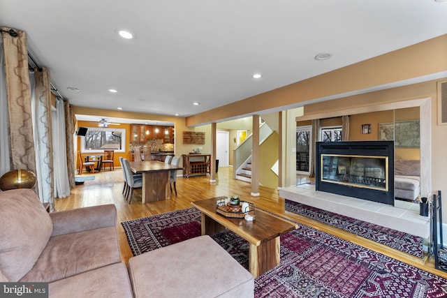 living room featuring recessed lighting, a fireplace, stairway, and wood finished floors