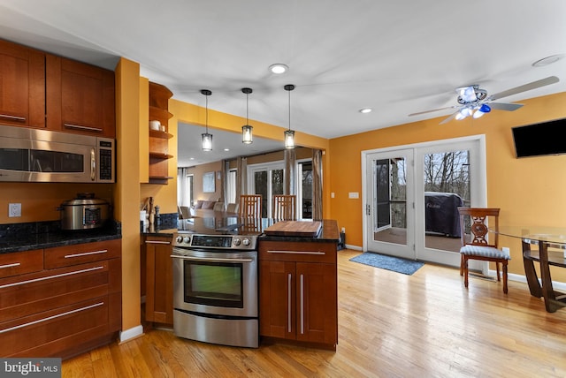 kitchen with dark countertops, light wood-style floors, a peninsula, and appliances with stainless steel finishes