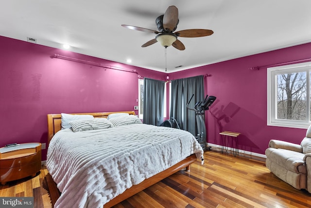 bedroom with ceiling fan, wood finished floors, and baseboards