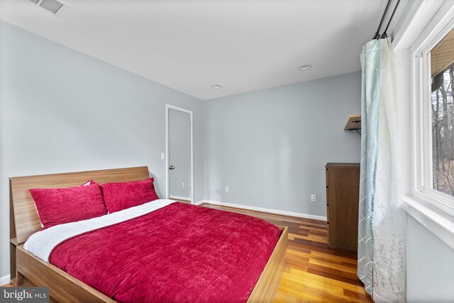 bedroom with baseboards, visible vents, wood finished floors, and recessed lighting