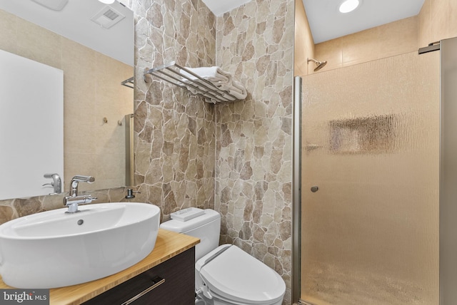 bathroom with toilet, vanity, visible vents, tile walls, and a shower stall