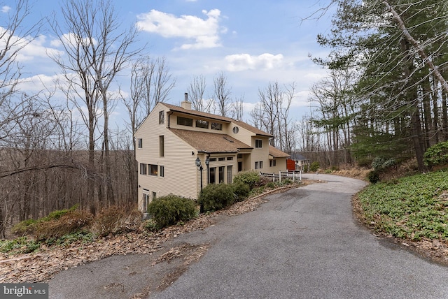 exterior space with a shingled roof and a chimney