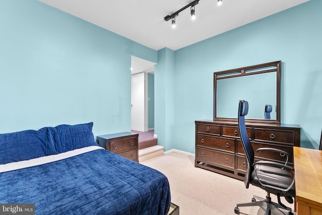 carpeted bedroom with baseboards and track lighting