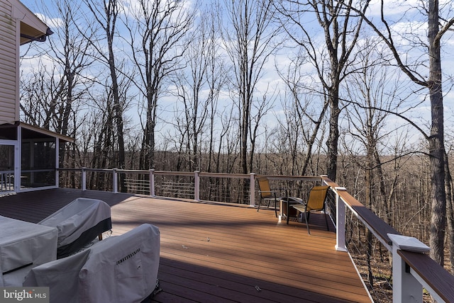 deck with a sunroom and a view of trees