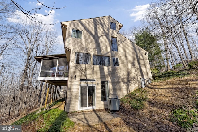 rear view of property with central AC unit and a sunroom