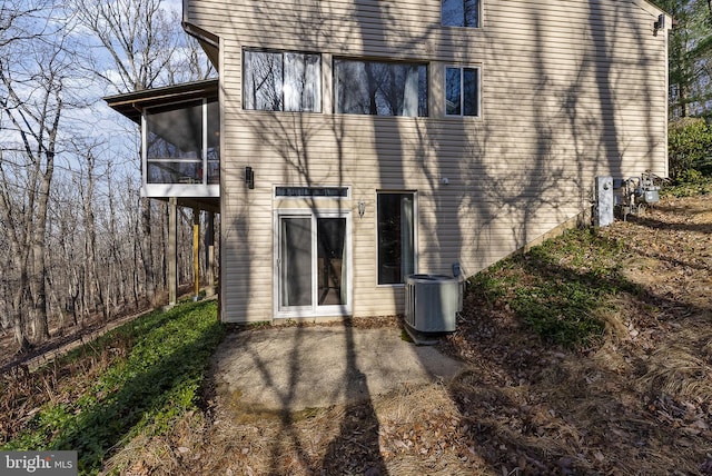 back of property with central air condition unit, a sunroom, and a patio