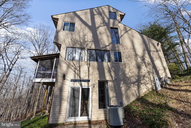 rear view of property featuring a sunroom and central AC unit