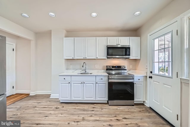 kitchen featuring white cabinetry, sink, light hardwood / wood-style flooring, and appliances with stainless steel finishes