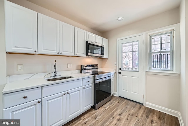 kitchen featuring sink, light hardwood / wood-style flooring, stainless steel appliances, light stone countertops, and white cabinets