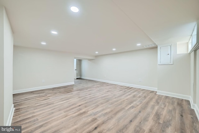 basement with electric panel and light hardwood / wood-style floors