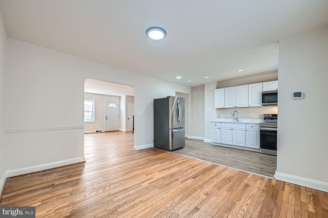 kitchen with white cabinetry, stainless steel appliances, light hardwood / wood-style floors, and sink